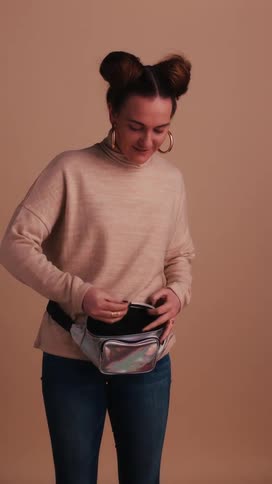 Woman takes snack from fanny pack and eats it and smiles