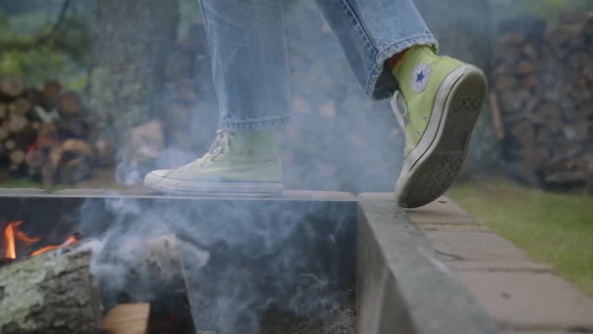 A person is walking around the edge of a bonfire