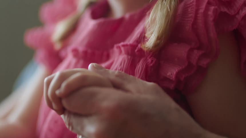 Pan from little girls face to holding hands with her elderly grandpa