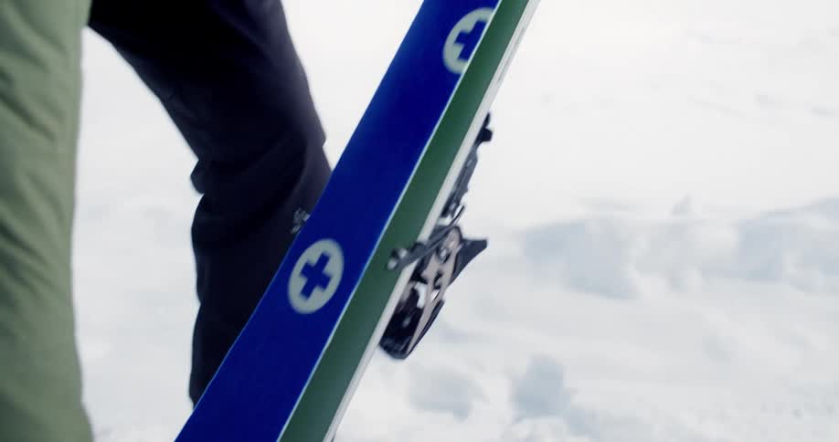A person putting a sticker over their ski outdoors in the snow