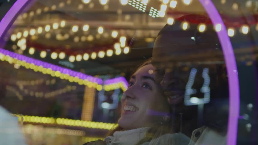 A young man girl and boy sitting together romantically smiling and laughing as they sit in front of glass