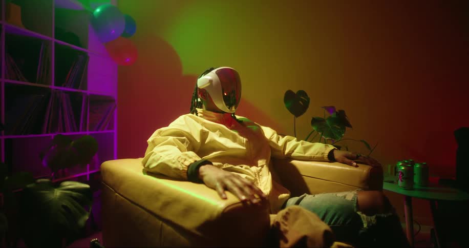 A man wears a reflective face mask while sitting on a chair