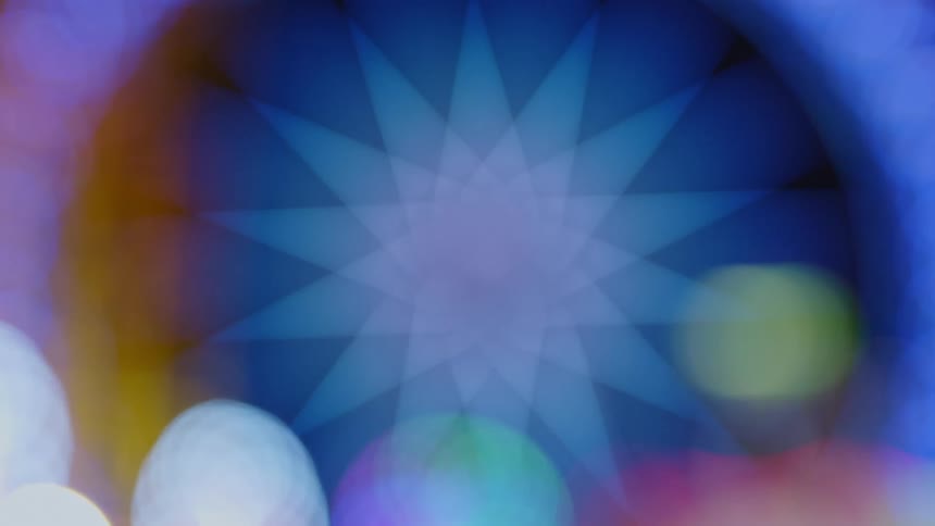 A geometrical star shape moves and changes colors as outside circles of colored light glow