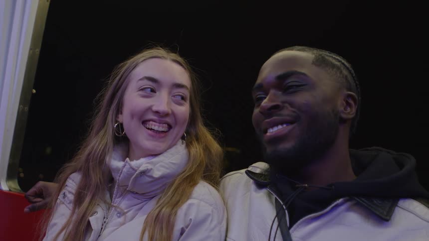 A man and woman sitting together the mans arm around the womans shoulders as they smile and laugh at teach other