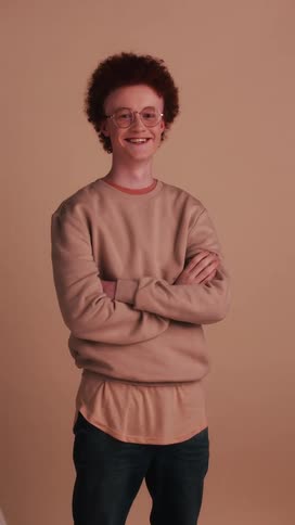 A young boy stands in front of a back drop and laughs and smiles