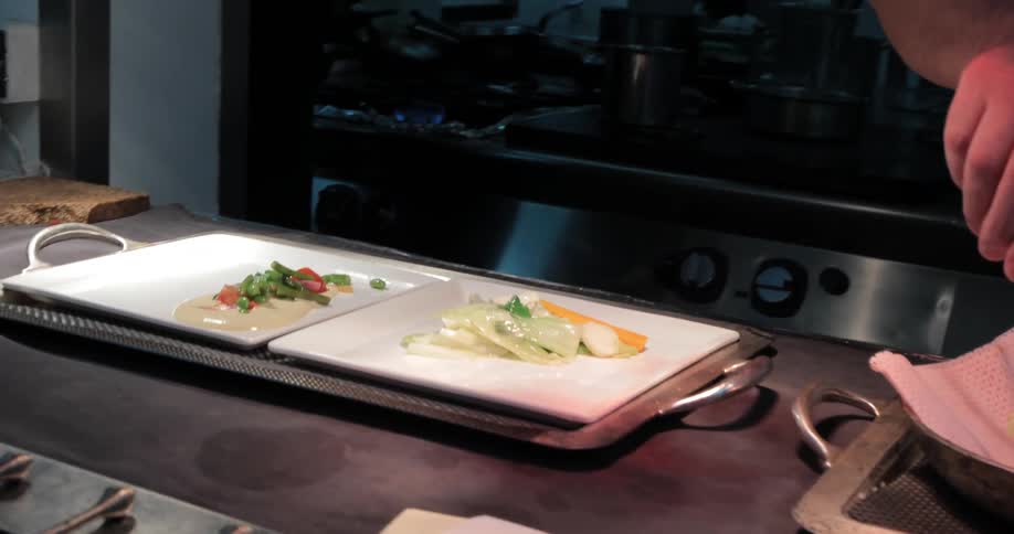 A chef is placing food on a dish