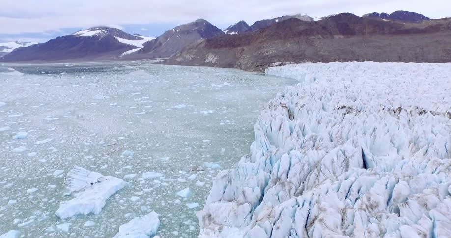 Icebergs line a frozen waterbody between mountains