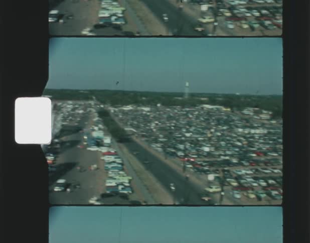 A view from a tall ferris wheel shows a huge parking lot near to a roller coaster