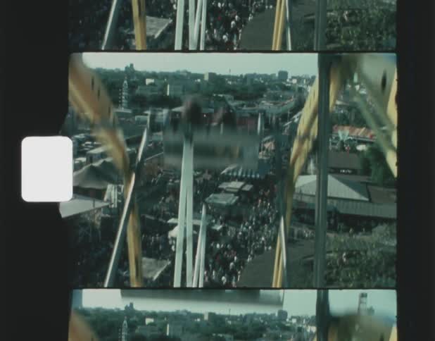 People ride on a ferris wheel as the cars rise high about the fairgrounds