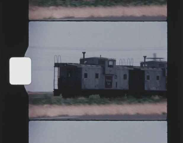 Train with two cabooses moves along track in countryside