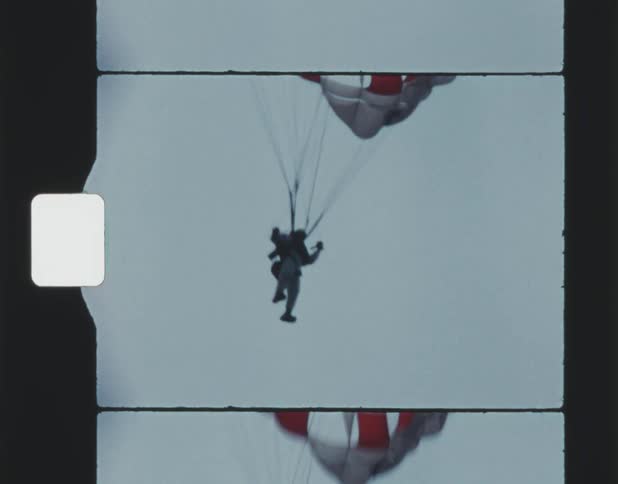 A parachutist holds the lines as they float down with their parachute