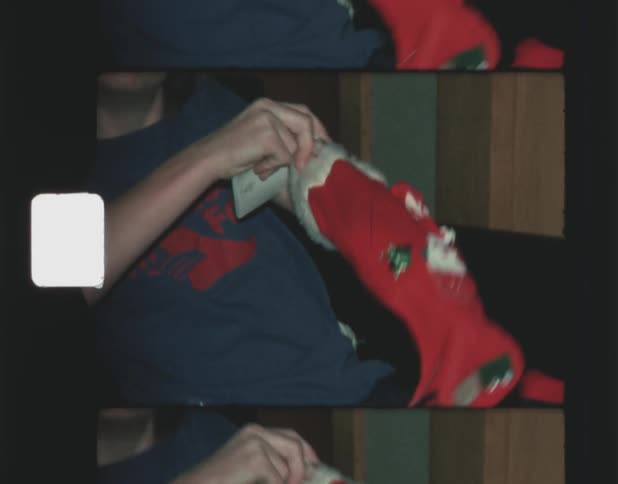 Old film footage of a boy laughing as he takes items out of a christmas stocking