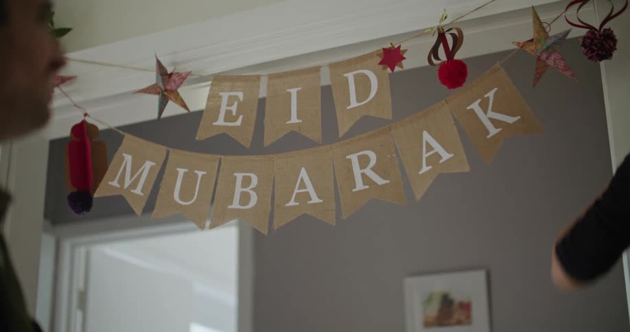 A woman putting up a banner across a beam smiling and laughing looking at the man next to her