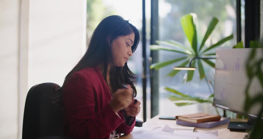 A woman takes out paper to write on while sitting at her desk