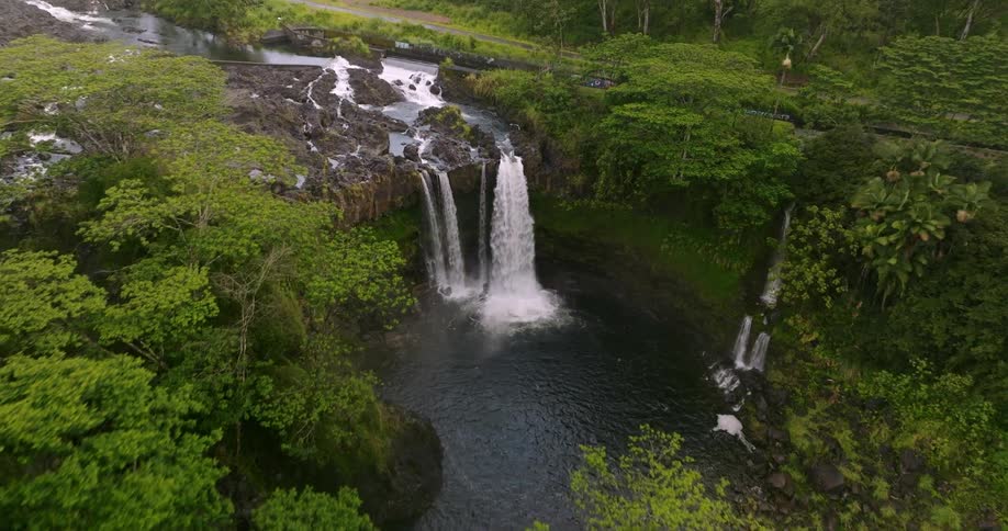 Water forms rapids through river before it flows over cliff in multiple waterfalls in forest
