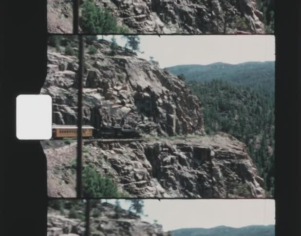 Old film footage of a train traveling through a mountain range