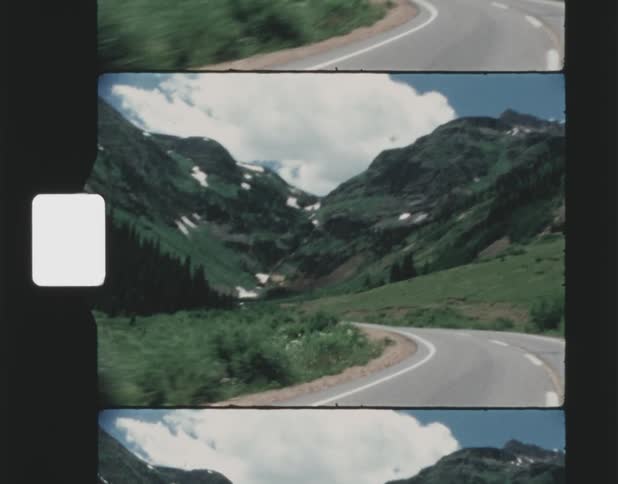 A road bends as it leads towards a towering mountain range