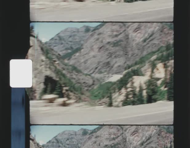 Film footage of mountains and pine trees are displayed
