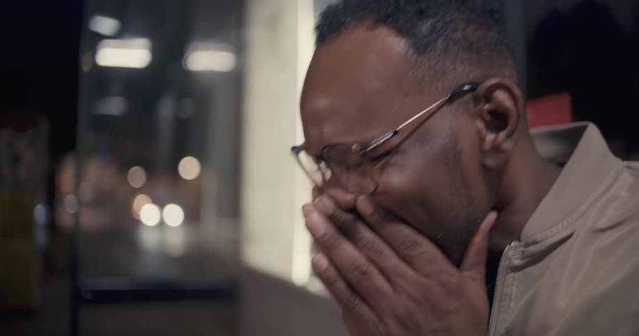 A man smiles and laughs as he covers his mouth with his hands