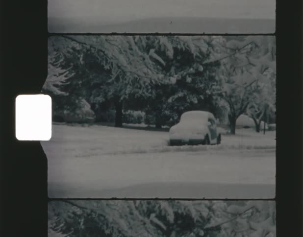 A snow covered car parked on a street in winter