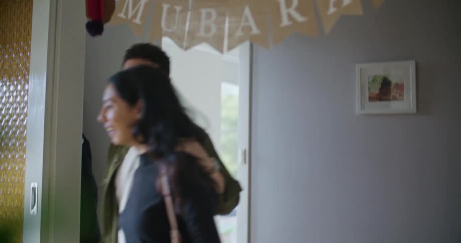 A man and woman arrive at a house for a party for eid mubarak during the day