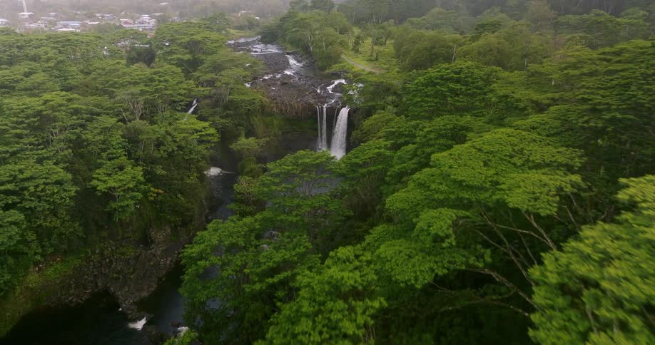 Aerial view of a waterfall in a forest is displayed