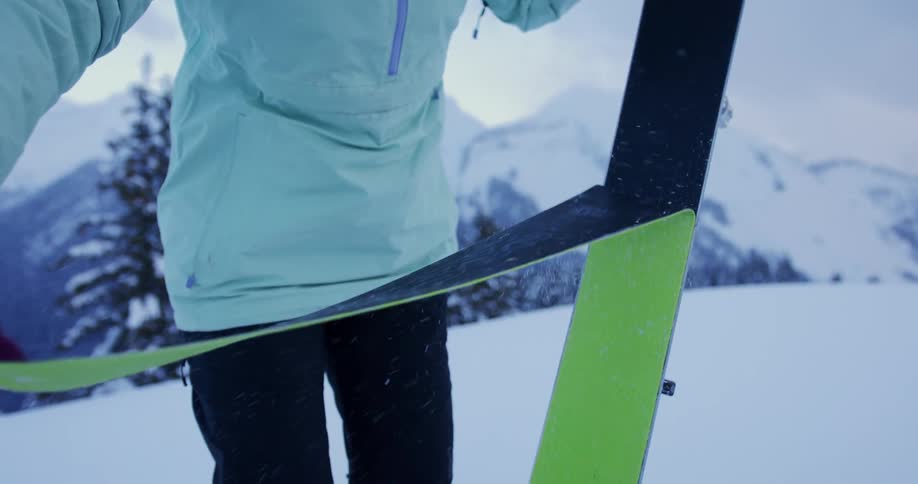 A woman pulling off a ski cover while standing outside in the snow