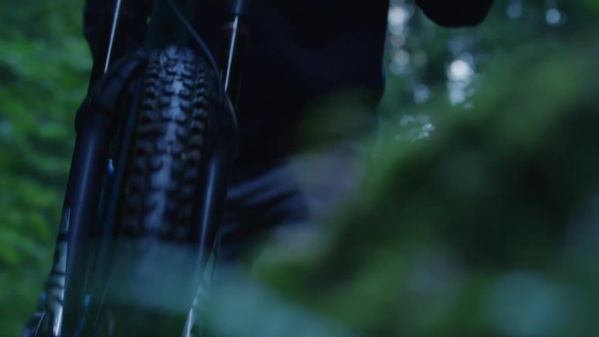 Cyclist with helmet jacket and pants carries mountain bicycle in the green woods