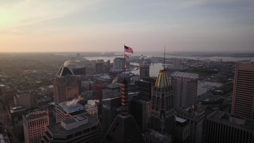 Aerial view of skyscrapers and american flag attached to pole flapping in the city of Baltimore