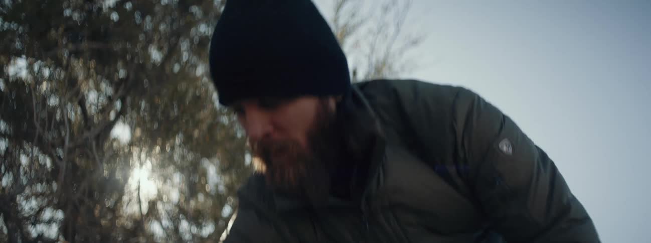 A man is unpacking his bag in a wooded area