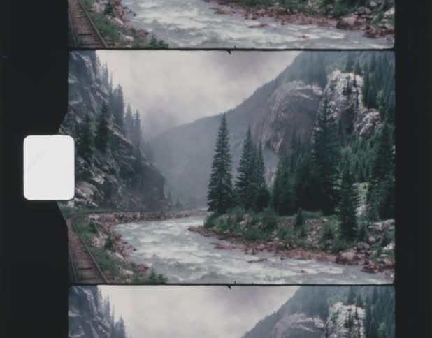Film footage of a river near mountain range is displayed