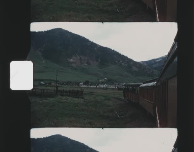 Old film footage of a train traveling past hills