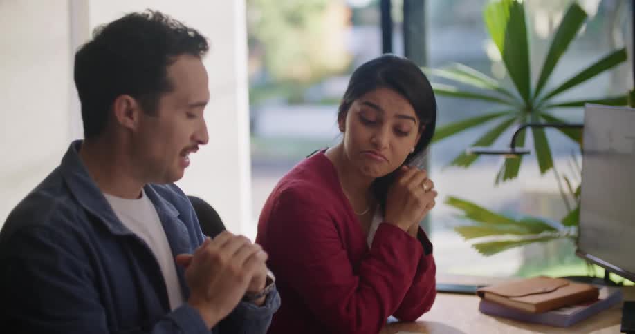 Businessman and businesswoman sit at desk exchanging opinions at the office