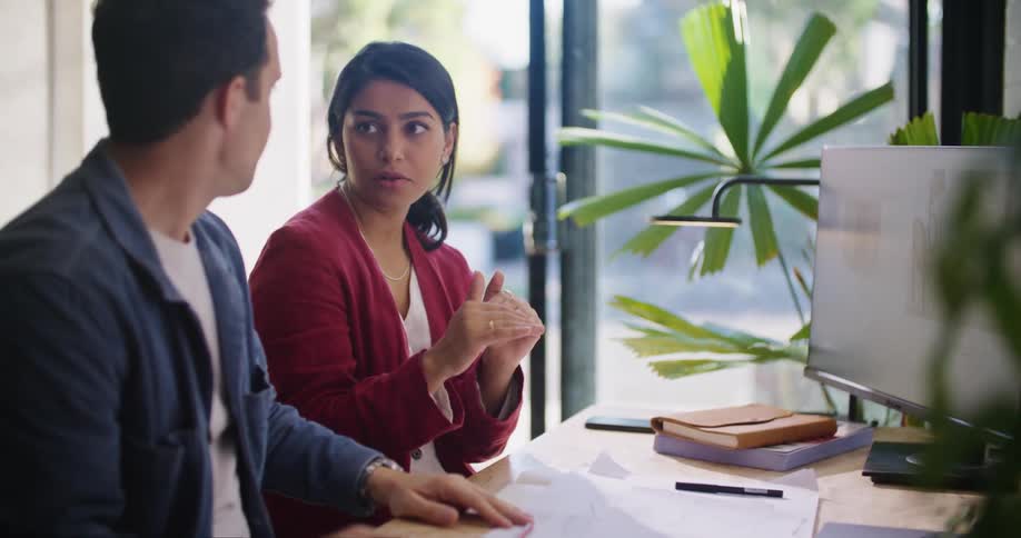 Two colleagues discuss work at a desk