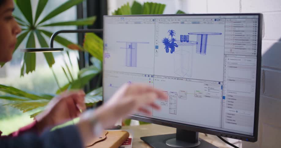 A man and woman in an office talk as they point at a computer screen