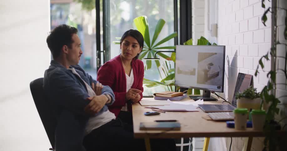 Two coworkers looking frustrated while working at an office desk