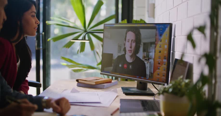 A man and woman talking to a man on a computer