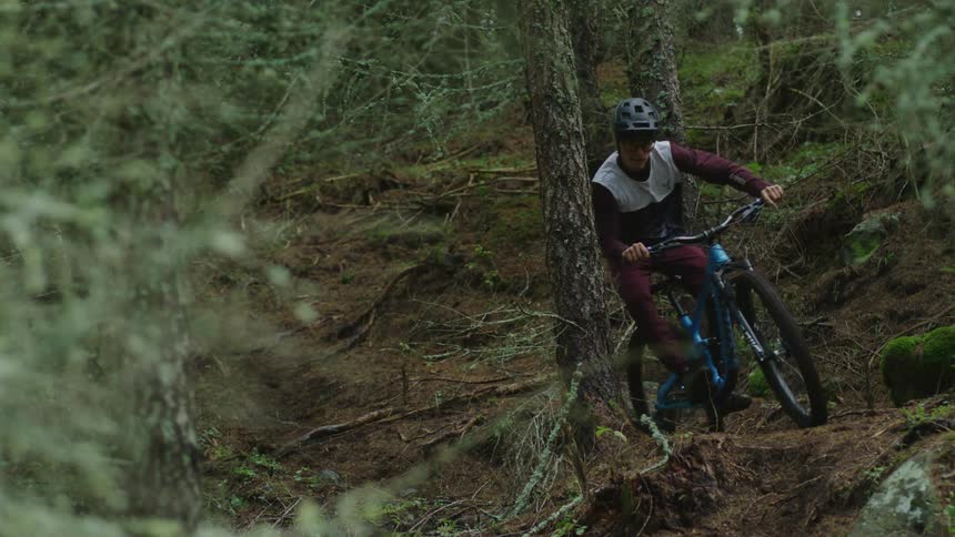 A young boy riding his bike through the forest on a path