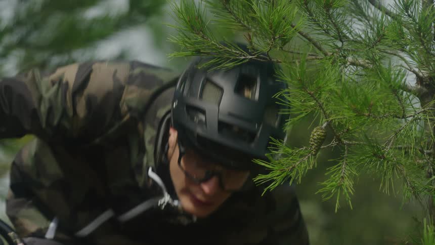 A male is riding his bike in a wooded area