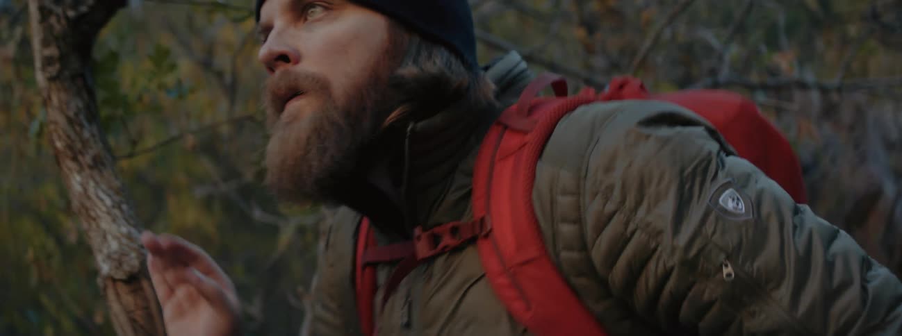A man is hiking through a forest during autumn season
