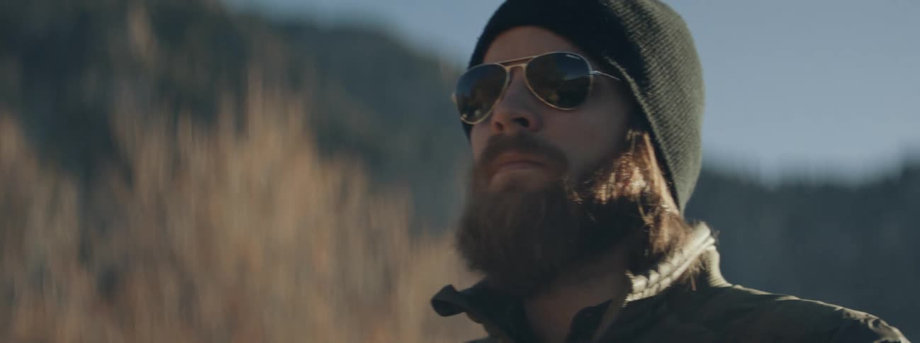 A man putting on sunglasses outdoors