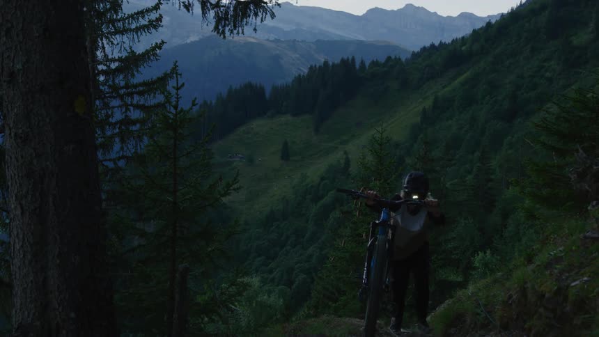 A male is bringing his bike up a hill landscape