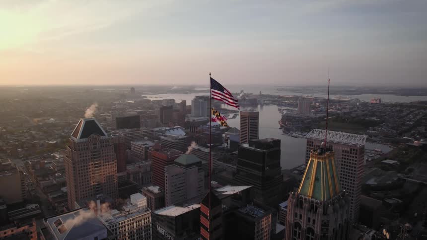 Aerial view of the American flag above a downtown city while sun is setting