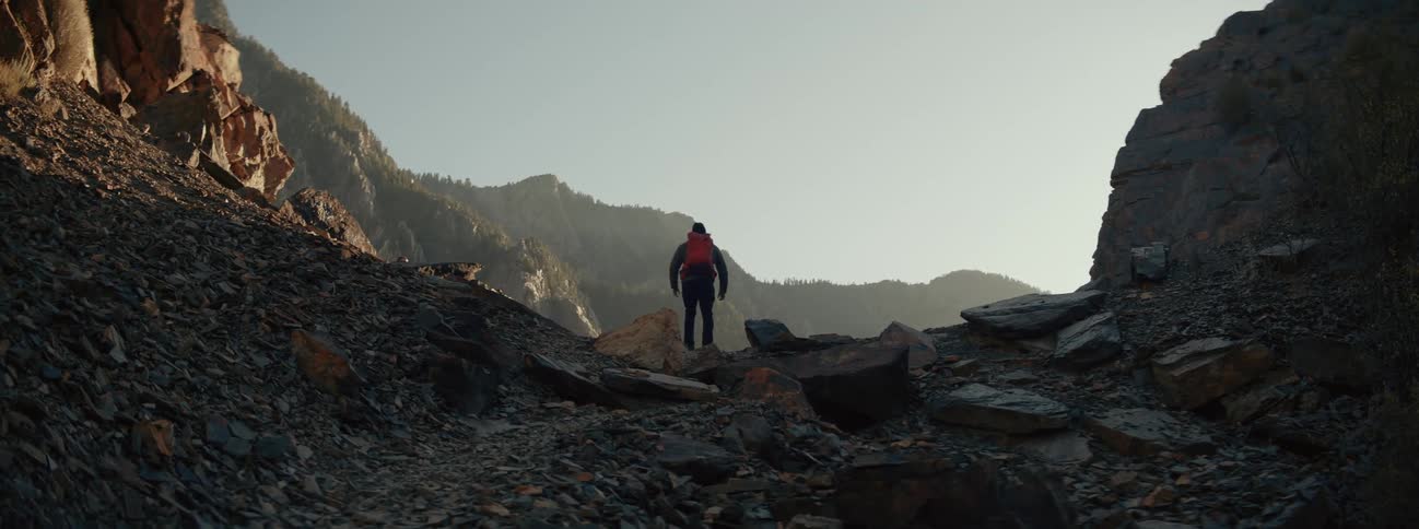 A person wearing a backpack treks through a canyon