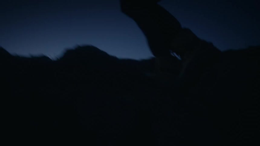 Photographer carrying camera climbs slope at night