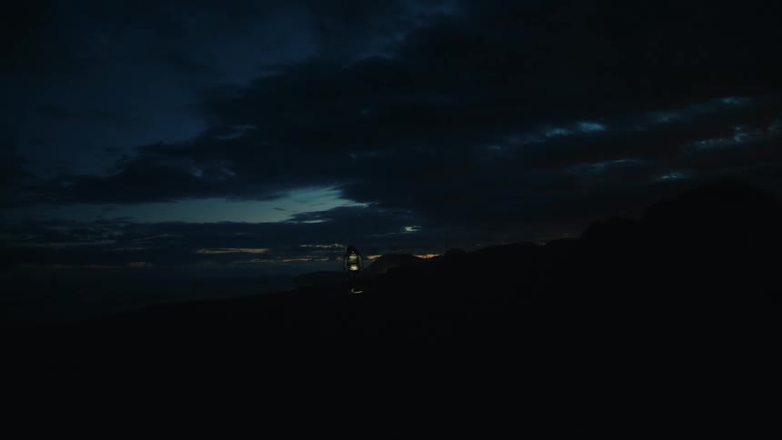 A person with a headlamp walks toward the camera at night