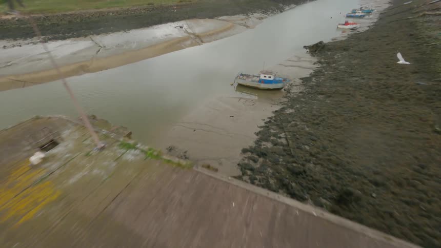Several boat are lined up along the muddy banks of a river