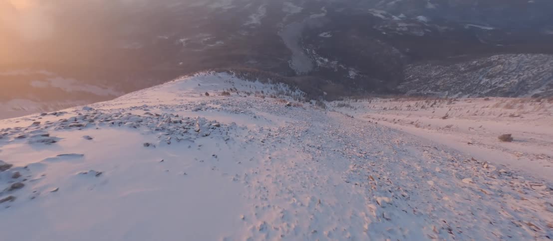 A sped up aerial view of a snow covered mountain with large steep slopes