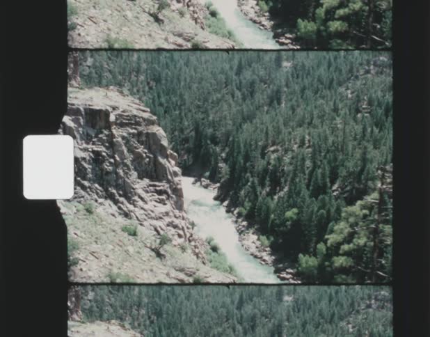Landscape of river flowing down valley next to forest seen from high mountain
