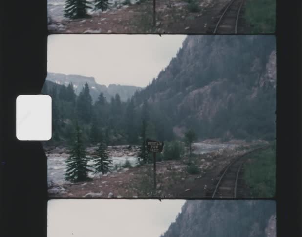 Landscape of high mountains seen from steam train running along railway track